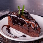 Piece of sachertorte sachr cake on white plate. Top view, copy space